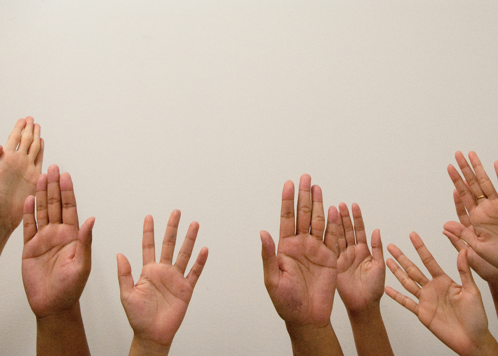 Hands raised in front of a white wall