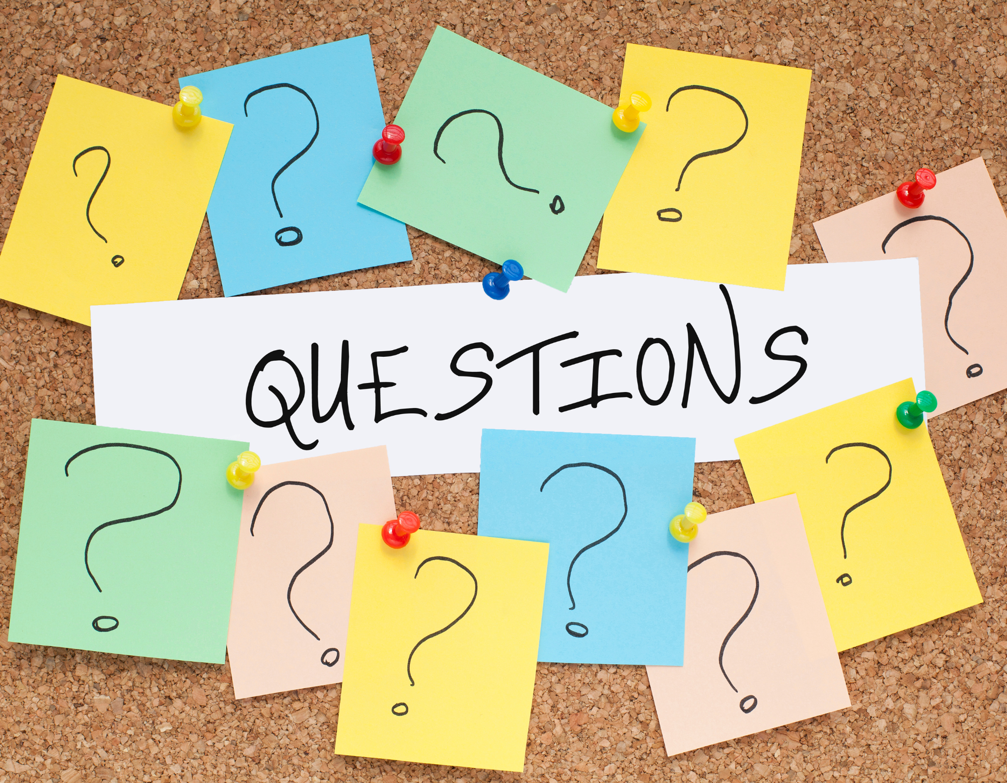 The word "Questions" on a bulletin board surrounded by sticky notes with questions marks drawn on them